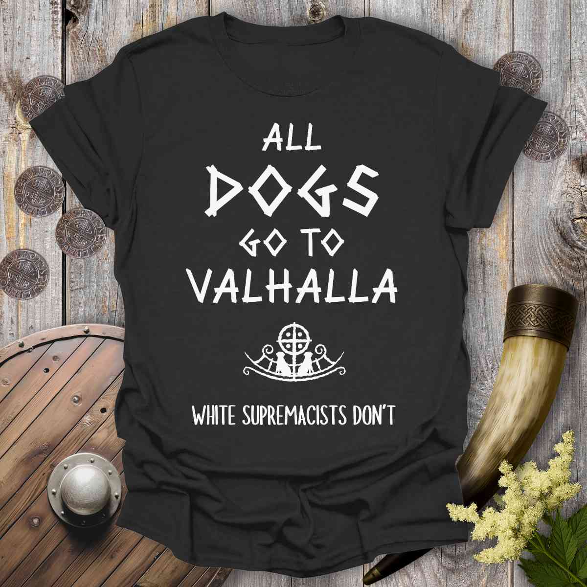Black t-shirt with 'All dogs go to Valhalla, white supremacists don't' text on a wooden background.