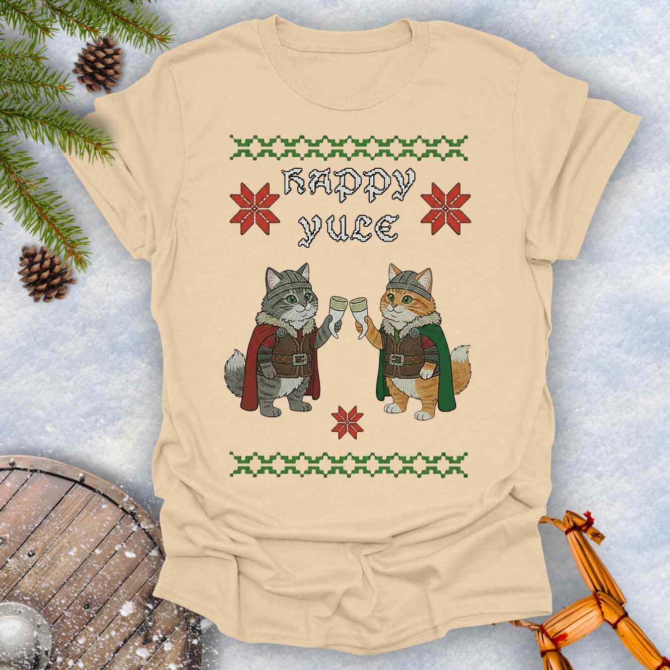 Beige Sand colored t-shirt with Holiday festive design, ugly sweater pattern style, of two Viking cats holding drinking horns and 'Happy Yule' text, surrounded by Christmas decorations on a snowy background.