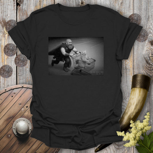 Black t-shirt with a graphic of a Viking and a cat in a shopping cart, sprinting on a parking Lot.
