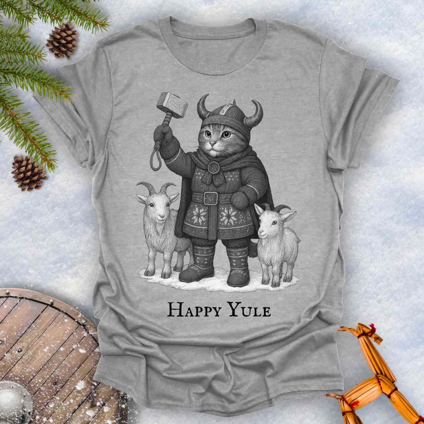 Gray Sports grey colored t-shirt with a black and white graphic of a Viking cat in winter gear, holding hammer Mjölnir, surrounded by two goats. 'Happy Yule' text under the image.