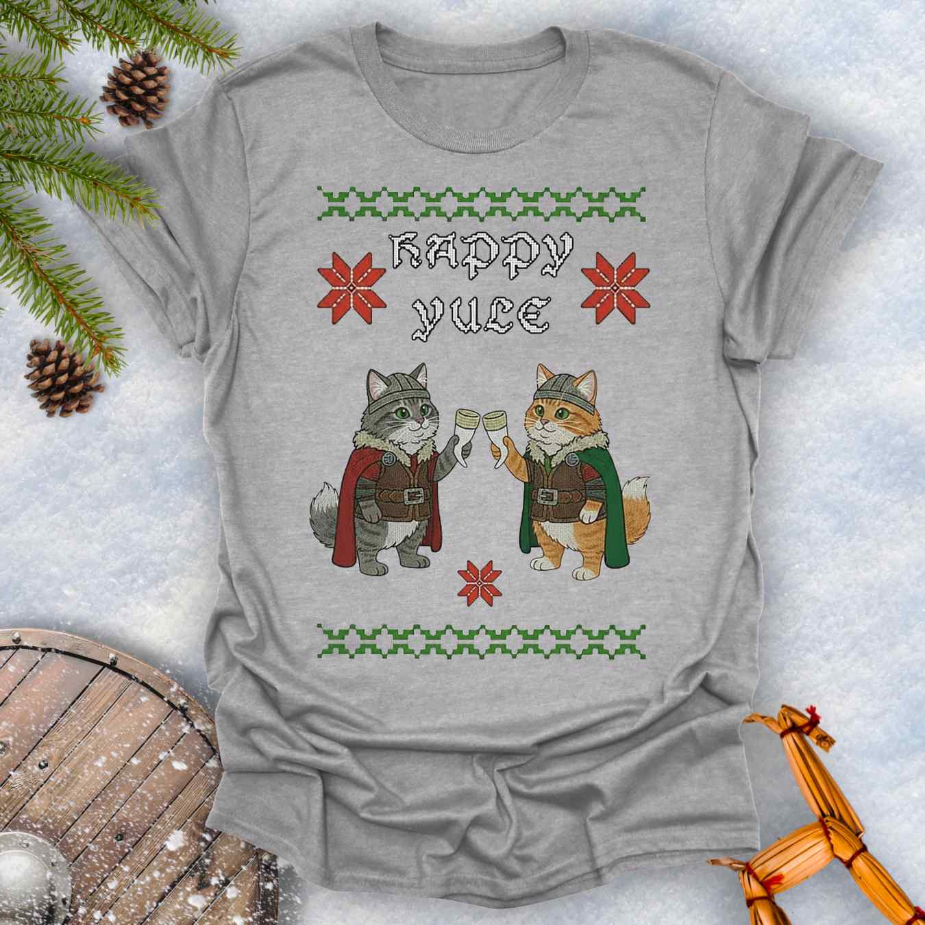 Gray colored t-shirt with Holiday festive design, ugly sweater pattern style, of two Viking cats holding drinking horns and 'Happy Yule' text, surrounded by Christmas decorations on a snowy background.