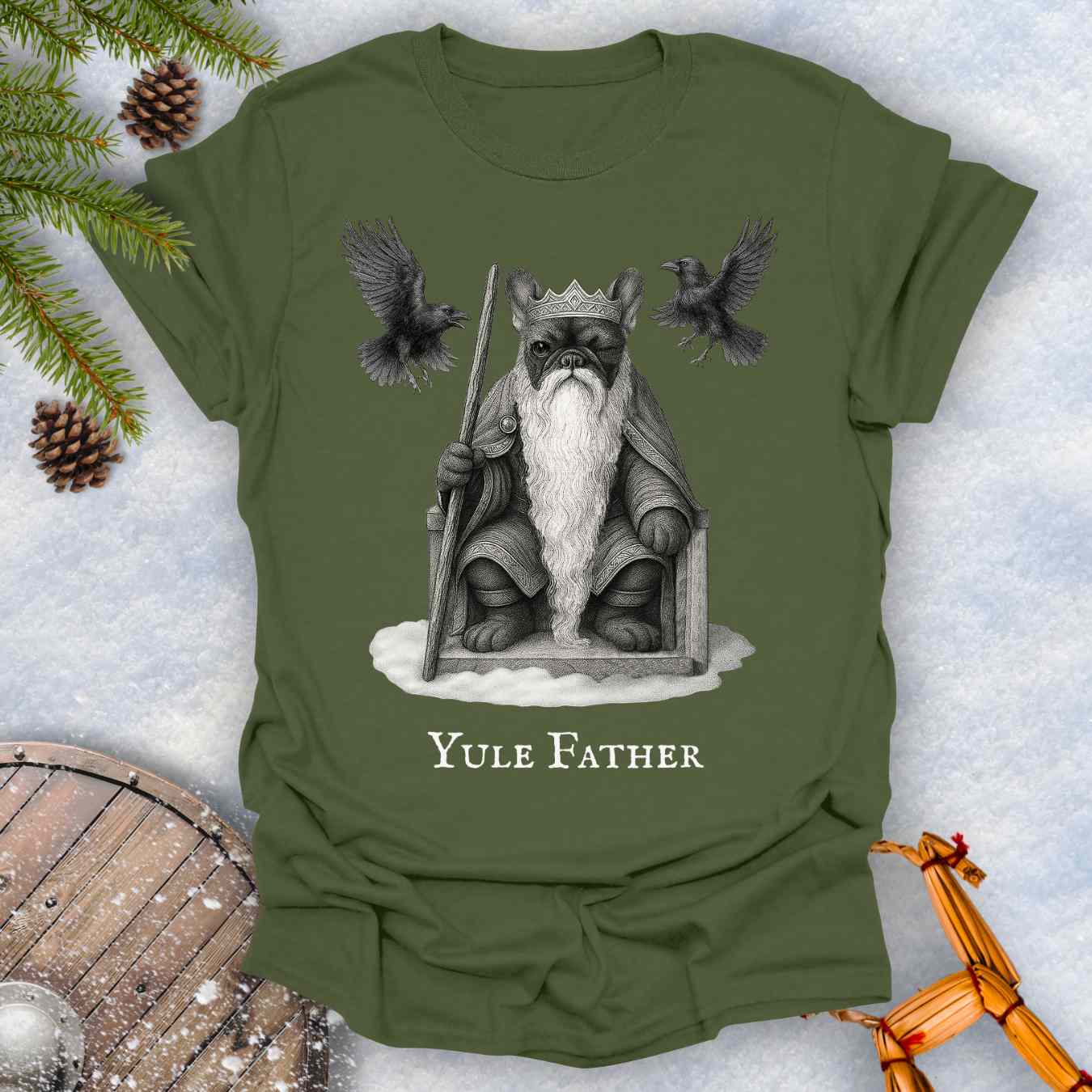 Green t-shirt with 'Yule Father' design featuring a French bulldog dog as the aesir Odin, with a beard and a crown, surrounded by two ravens on a snowy background.
