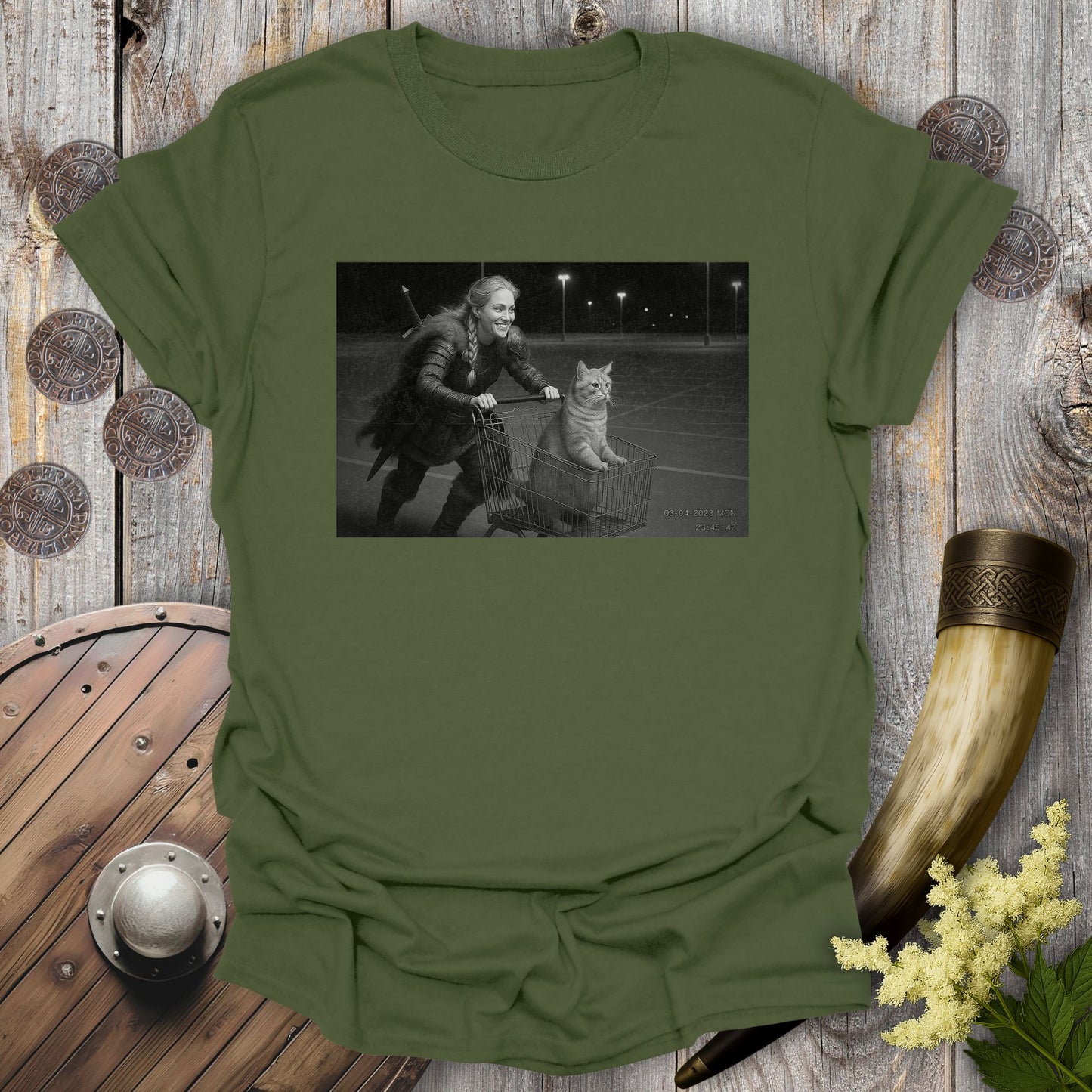 Military Green t-shirt with a graphic of a Viking Shieldmaiden and a tabby cat in a shopping cart, sprinting on a parking Lot.
