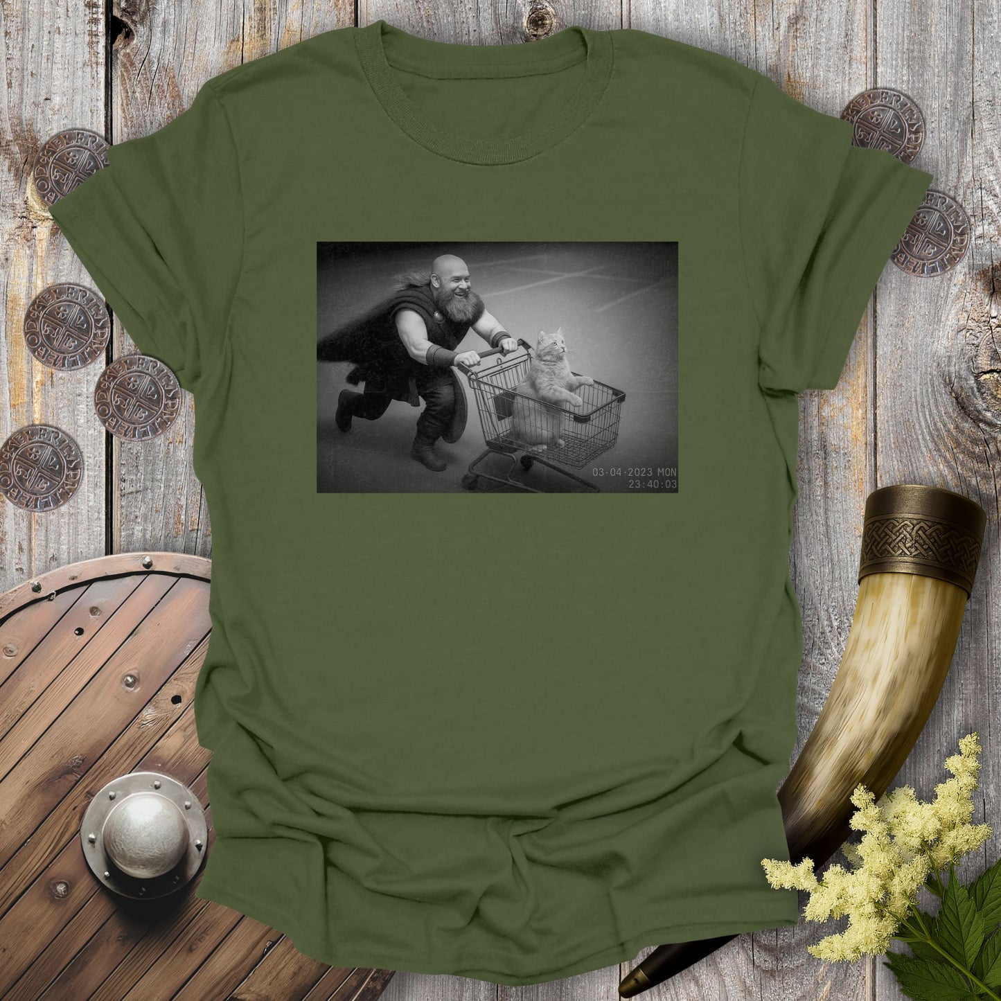 Military Green t-shirt with a graphic of a Viking and a cat in a shopping cart, sprinting on a parking Lot.
