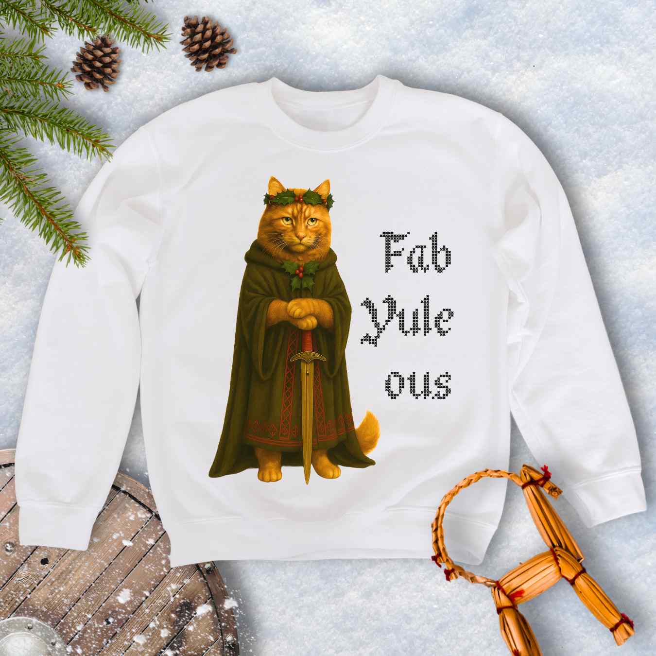 White sweatshirt with a Shieldmaiden cat in a cloak and sword graphic and 'Fab Yule ous' cross stich lookalike text.