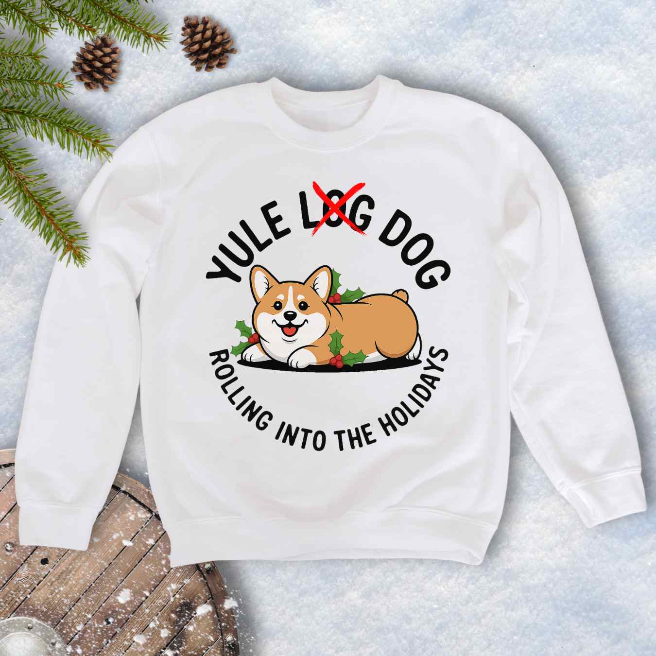 Beige Sand colored sweatshirt with a corgi holiday graphic and text "Yule Log Dog Rolling Into the Holidays" With "Log" crossed over in red, on a snowy background.