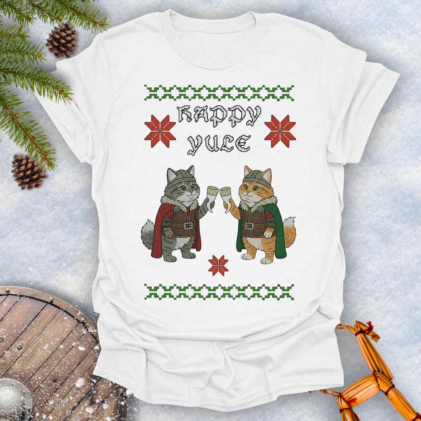 White t-shirt with Holiday festive design, ugly sweater pattern style, of two Viking cats holding drinking horns and 'Happy Yule' text, surrounded by Christmas decorations on a snowy background.