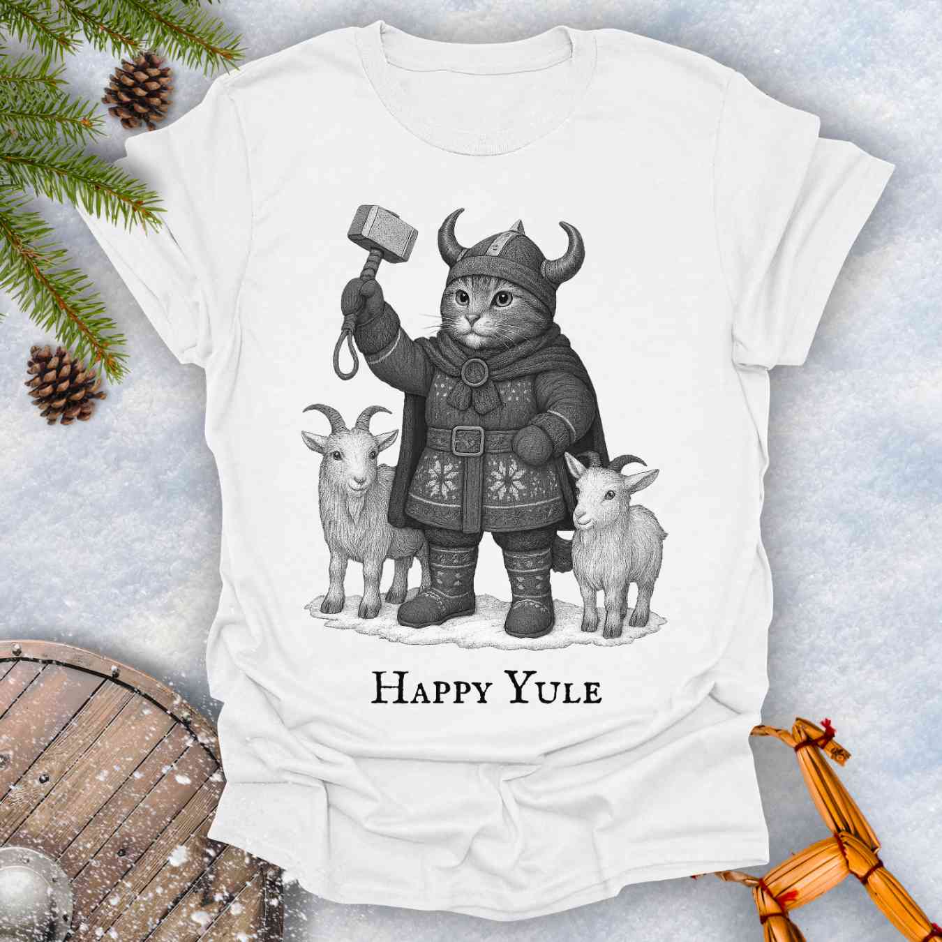 White t-shirt with a black and white graphic of a Viking cat in winter gear, holding hammer Mjölnir, surrounded by two goats. 'Happy Yule' text under the image.