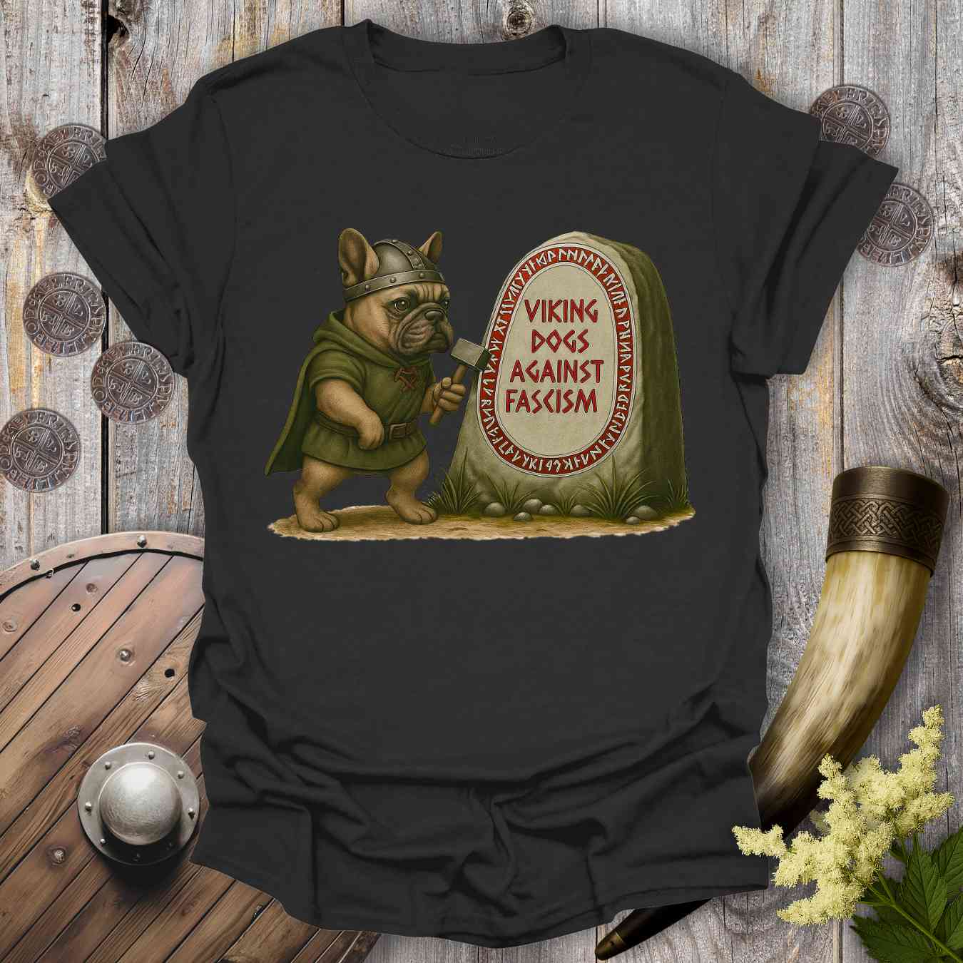 Black t-shirt with a graphic of a dog in Viking attire next to a gravestone with 'Viking Dogs Against Fascism' text, on a wooden background.