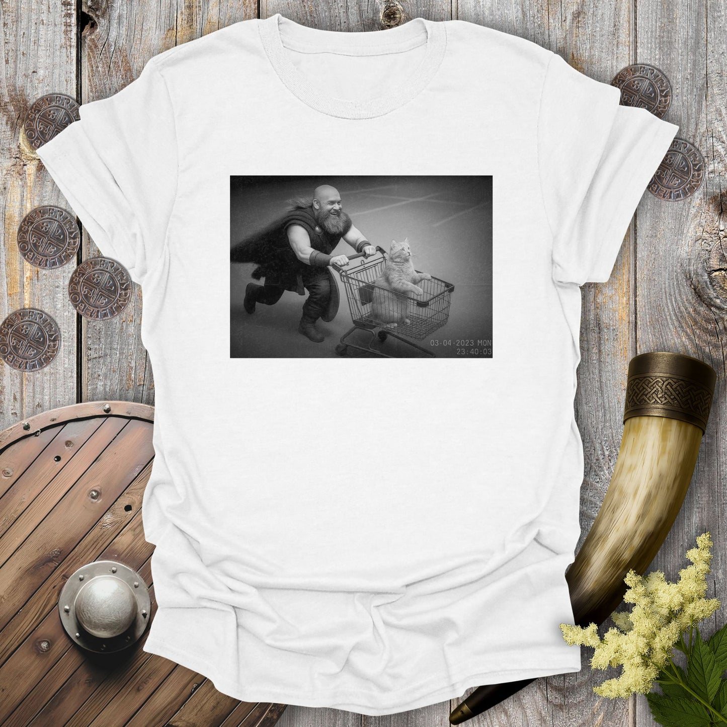 White t-shirt with a graphic of a Viking and a cat in a shopping cart, sprinting on a parking Lot.