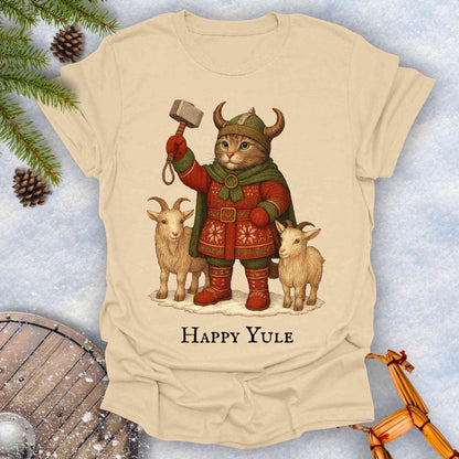 Beige sand t-shirt with a Thor lookalike cat in Viking costume, with goats and a hammer, text 'Happy Yule', on a snowy background.