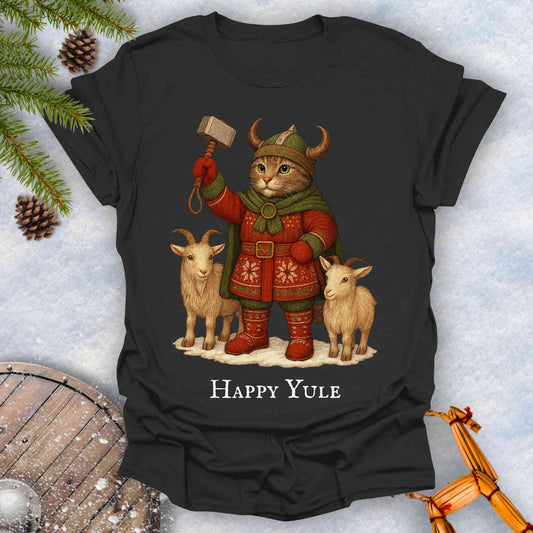 Black t-shirt with a cat in Viking attire holding a hammer, surrounded by goats and 'Happy Yule' text, on a snowy background.