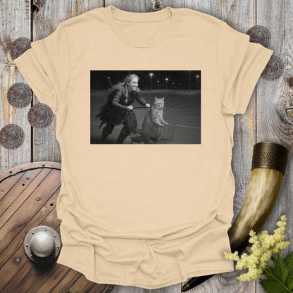 Beige Sand colored t-shirt with a graphic of a Viking Shieldmaiden and a tabby cat in a shopping cart, sprinting on a parking Lot.