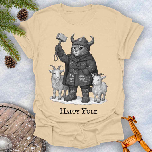 Beige Sand colored t-shirt with a black and white graphic of a Viking cat in winter gear, holding hammer Mjölnir, surrounded by two goats. 'Happy Yule' text under the image.