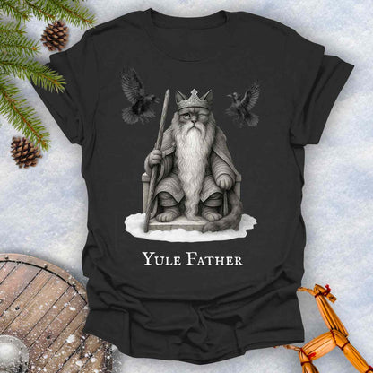 Black T-shirt with the aesir Odin reimagined as a black cat. Text 'Yule Father' design on a snowy background.