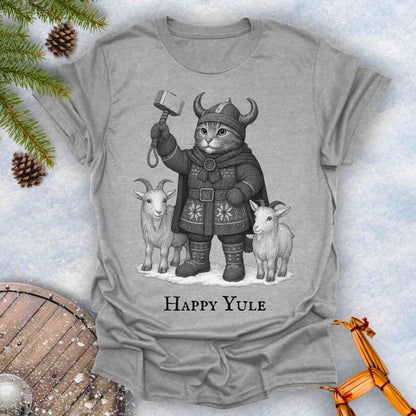Gray Sports grey colored t-shirt with a black and white graphic of a Viking cat in winter gear, holding hammer Mjölnir, surrounded by two goats. 'Happy Yule' text under the image.