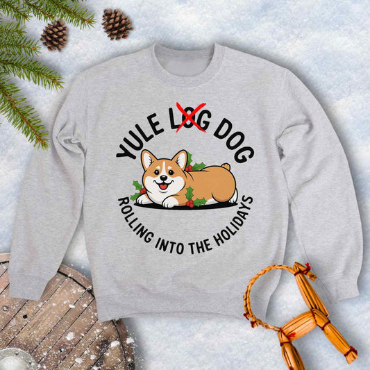 Gray ash colored sweatshirt with a corgi holiday graphic and text "Yule Log Dog Rolling Into the Holidays" With "Log" crossed over in red, on a snowy background.