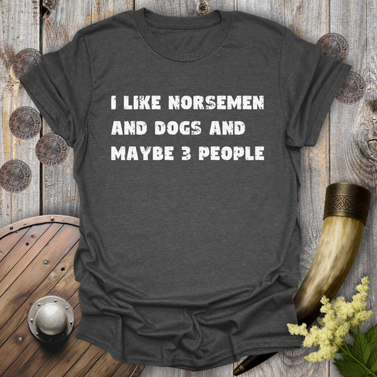 Gray dark heather t-shirt with white distressed text "I Like Norsemen and Dogs and Maybe 3 People" on a wooden background.