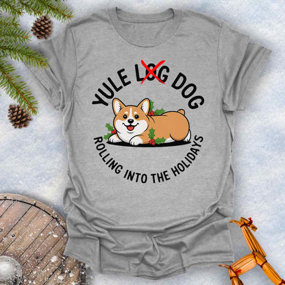 Gray Sports Grey colored T-Shirt with a Corgi holiday graphic and text "Yule Log Dog Rolling Into the Holidays" With "Log" crossed over in red, on a snowy background.