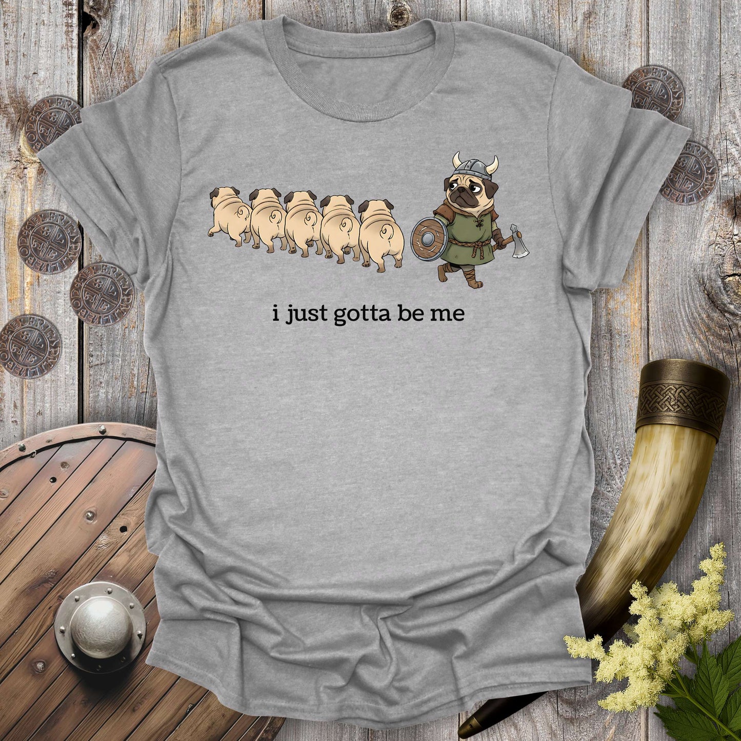 Gray sports grey t-shirt with cartoon Viking pug design and text "i just gotta be me" on a wooden background.