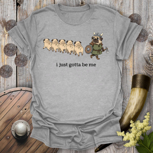 Gray sports grey t-shirt with cartoon Viking pug design and text "i just gotta be me" on a wooden background.