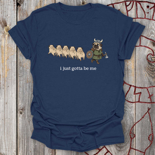 Navy blue t-shirt with cartoon design with a Viking Pug and text 'I just gotta be me' on a wooden surface