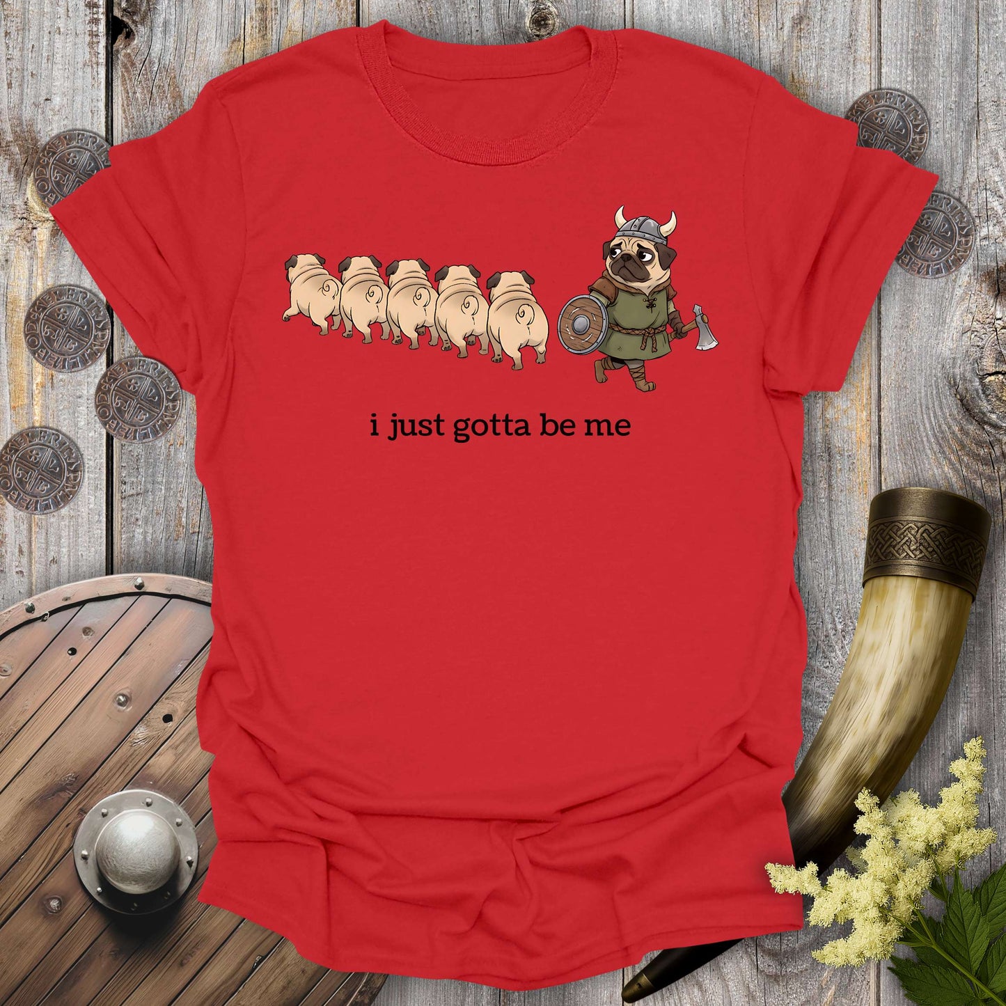 Red t-shirt with cartoon Viking pug design and text "i just gotta be me" on a wooden background.