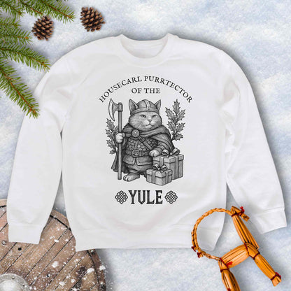 White sweatshirt with a cat in a Viking outfit and Christmas gifts with 'Housecat Purrtector of the Yule' text. 