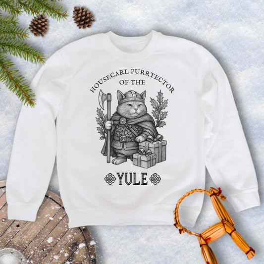 White sweatshirt with a cat in a Viking outfit and Christmas gifts with 'Housecat Purrtector of the Yule' text. 