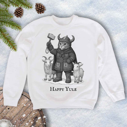 White sweatshirt with a black and white graphic of a Viking cat in winter gear, holding hammer Mjölnir, surrounded by two goats. 'Happy Yule' text under the image.