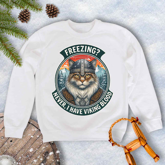 White sweatshirt with a graphic of a Viking Norwegian Forest Cat and text 'Freezing? Never, I have Viking blood' with a Nordic, retro sunset graphic in the background.