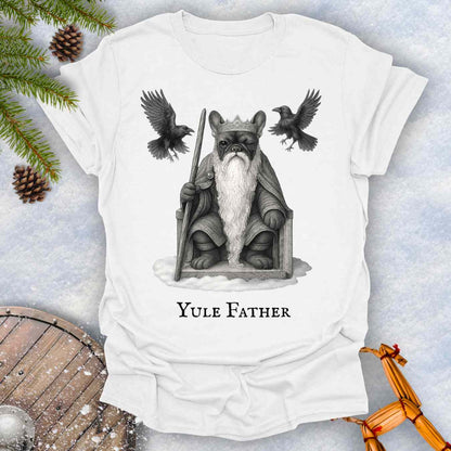 White t-shirt with 'Yule Father' design featuring a French bulldog dog as the aesir Odin, with a beard and a crown, surrounded by two ravens on a snowy background.
