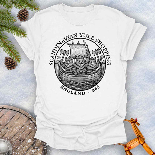 White t-shirt with a black graphic design of Viking cats in a ship. Text: Scandinavian Yule Shopping England 865