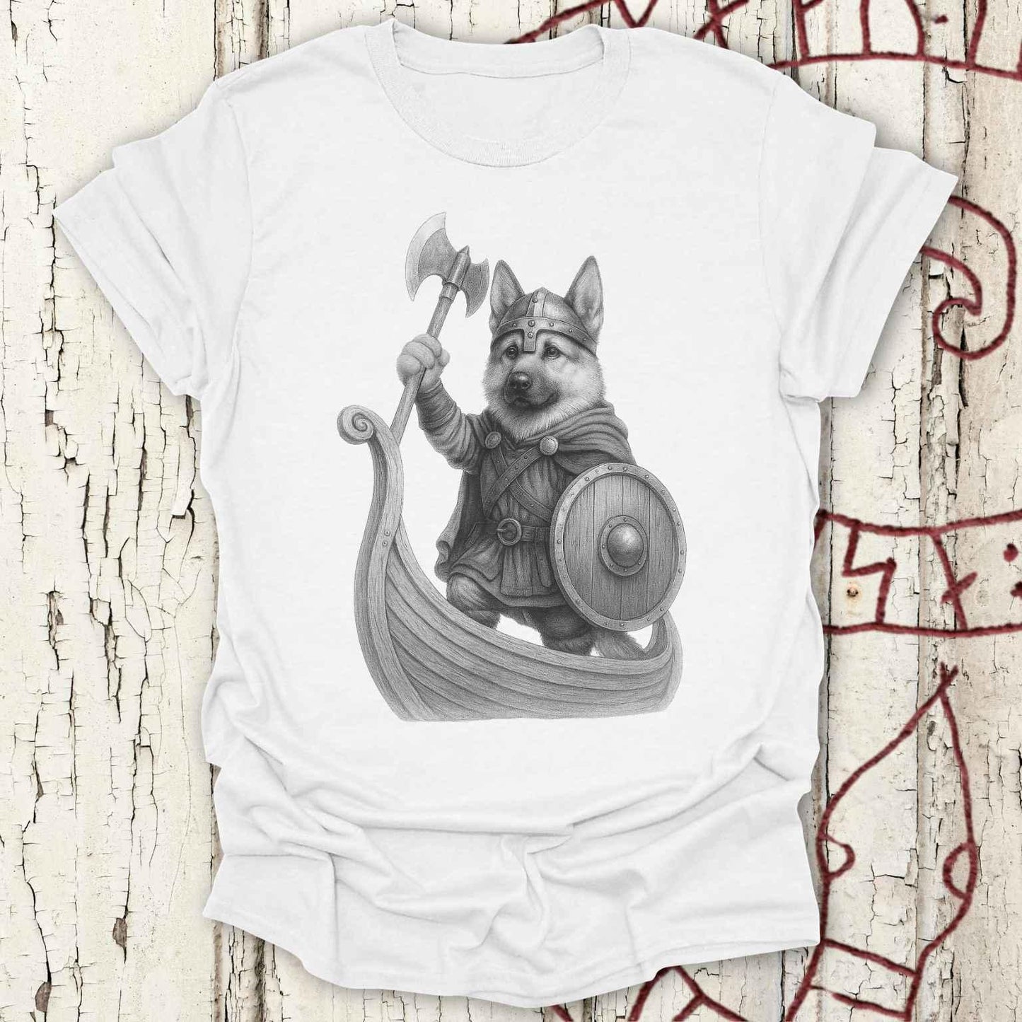 A white short-sleeve crewneck t-shirt featuring a detailed black and white graphic of a Viking dog wearing a helmet and standing in a boat with an axe and shield, displayed on a distressed white wood background with red rune markings.