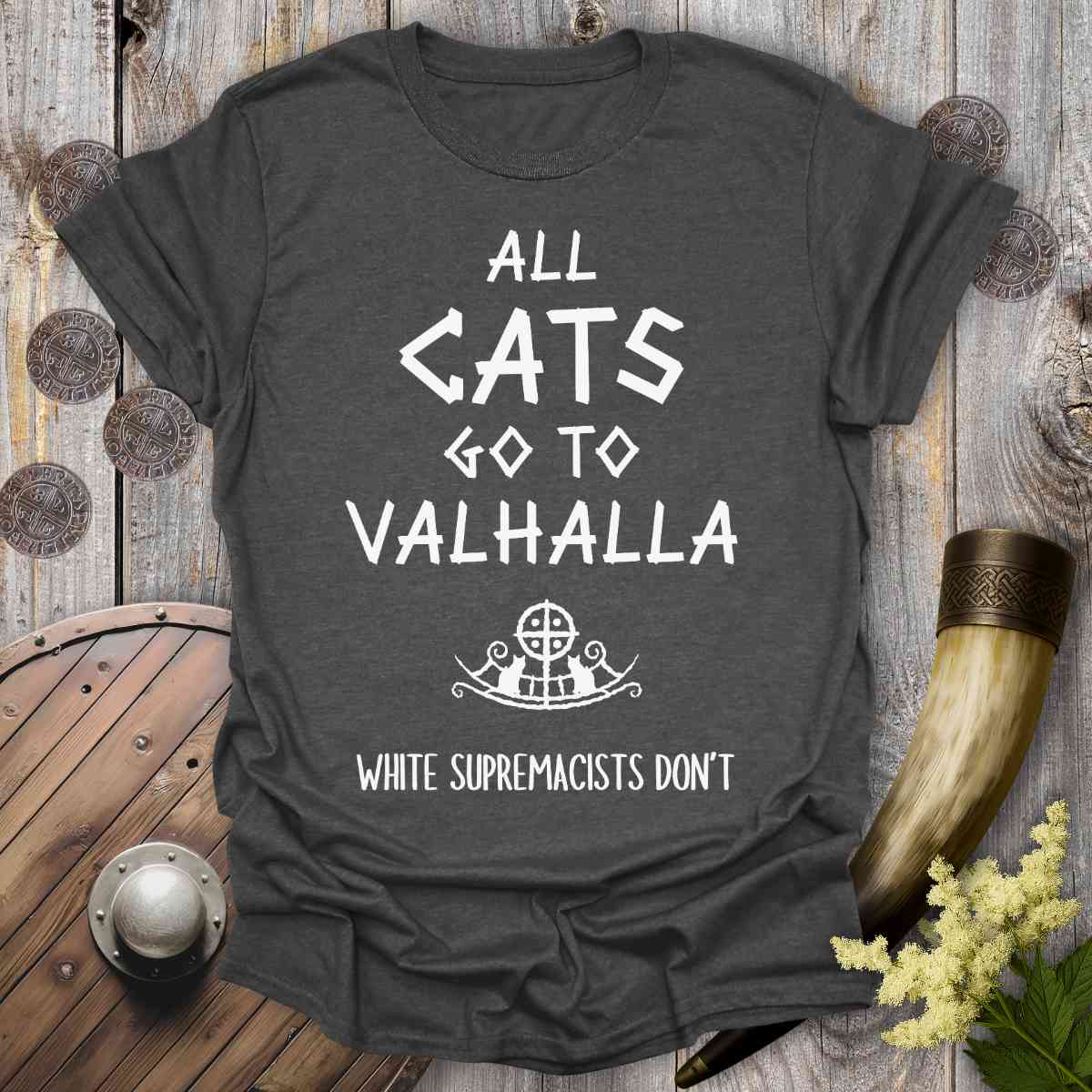 Gray t-shirt with 'All cats go to Valhalla, white supremacists don't' text on a wooden background.