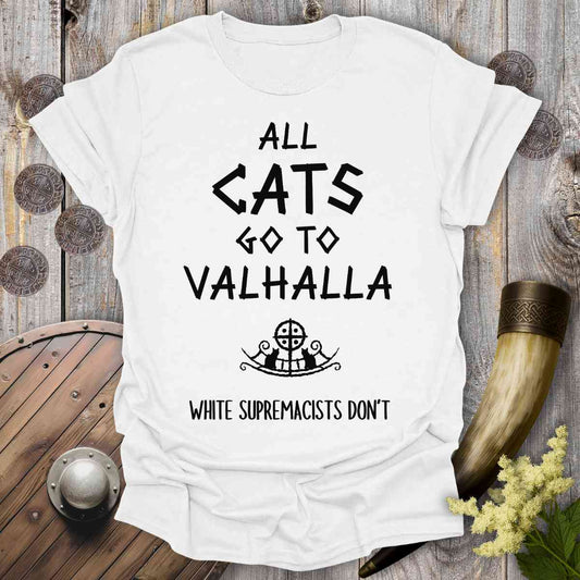 White t-shirt with text 'All cats go to Valhalla, white supremacists don't' on a wooden background.