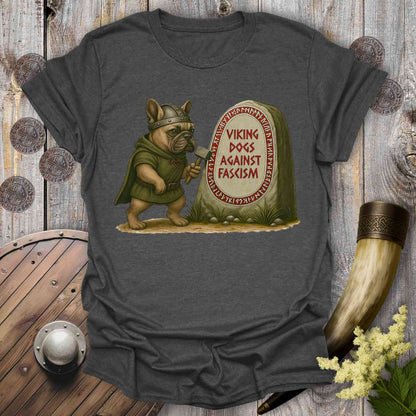 T-shirt with a Viking-themed graphic of a dog holding an ax and a stone with text 'viking dogs against fascism'. Placed on a wooden background.