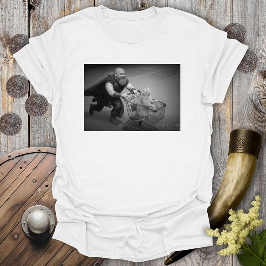 White t-shirt with a graphic of a Viking and a cat in a shopping cart, sprinting on a parking Lot.